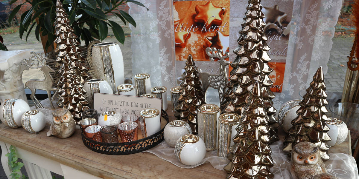 Stilvolle Kollektion von Dekorationsartikel für die Advents- und Weihnachtszeit, bestehend aus: Gold glänzenden Tannen und weißen Kerzenhaltern mit goldfarbenen Akzenten.