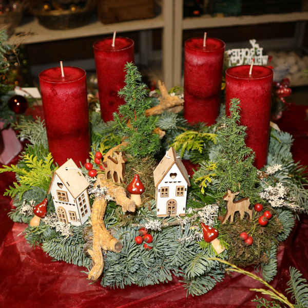 Verspielter Adventskranz mit kleinen Häuschen und Kerzen.