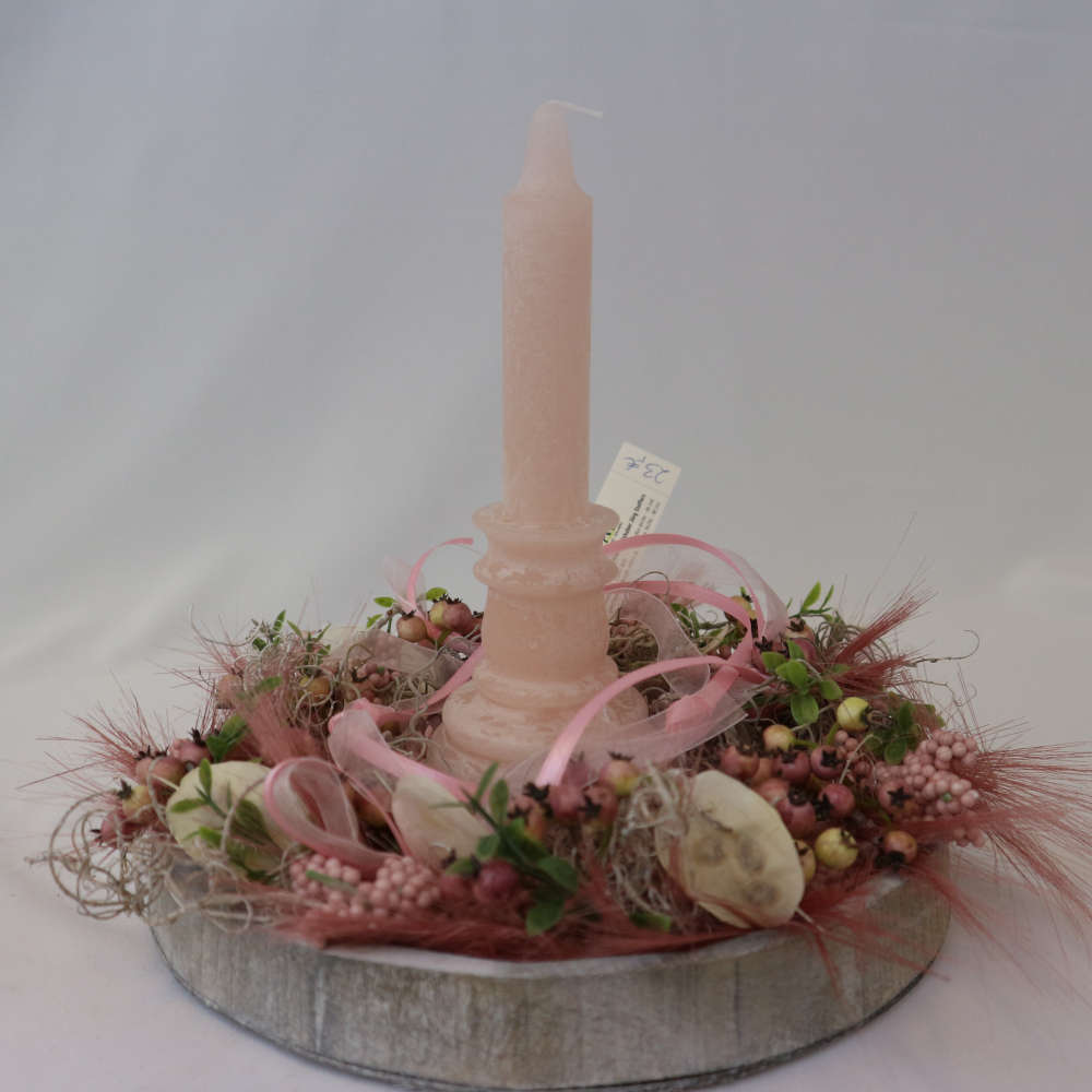 Eine rosa Kerze auf einem Tablett in Holzoptik wird von kleinen und großen Kunstbeeren umgeben.