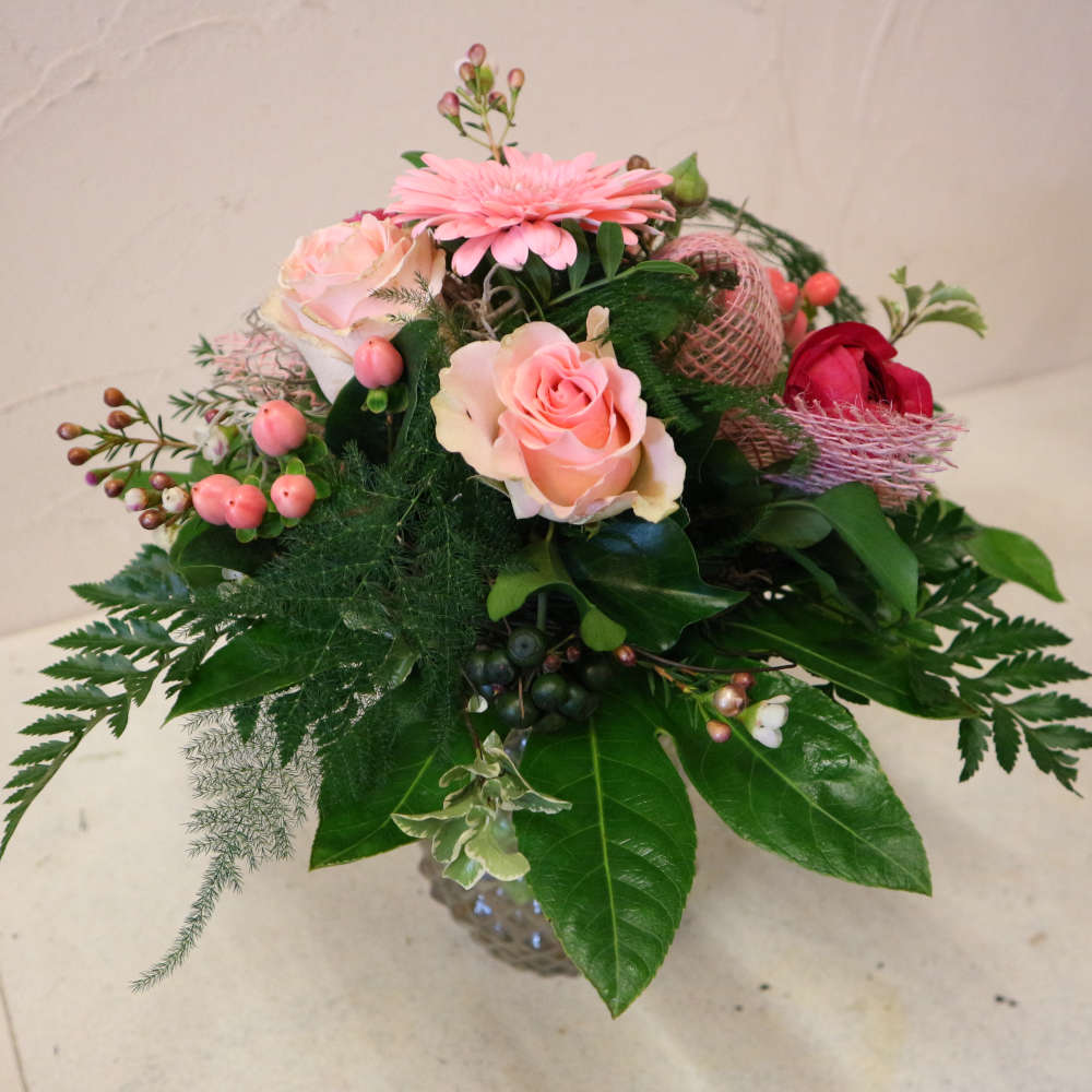 Ein kleiner, kompakt gebundener Blumenstrauß, bestehend aus rosa Gerbera, aufstrebenden Veroknika und rosa Rosenblüten.