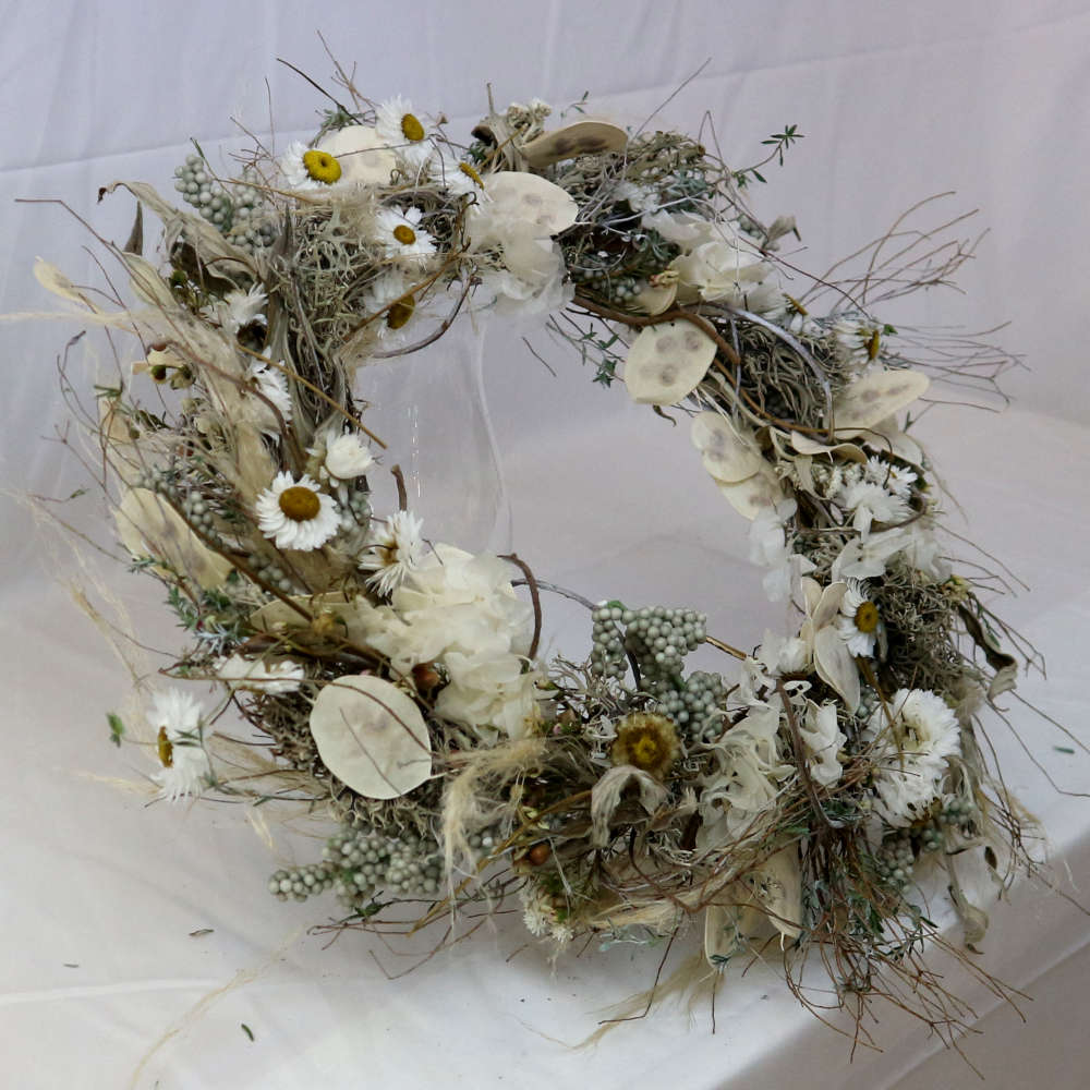 Ein weißer Kranz aus getrockneten Blumen. Unter anderem wurden Strohblumen und Hortensieblüten verwendet. Locker gewickelte Variante.