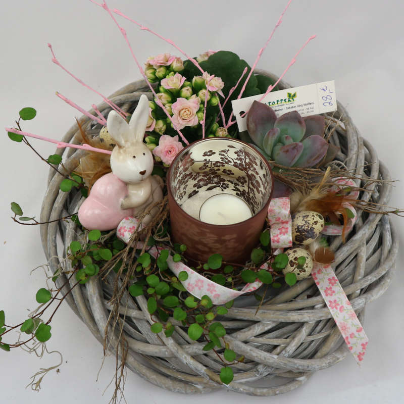 Eine mit Muehlenbeckia, Kalanchoe und Sukkulenten bepflanzte Schale mit Hasenfigur und Kerzenglas.