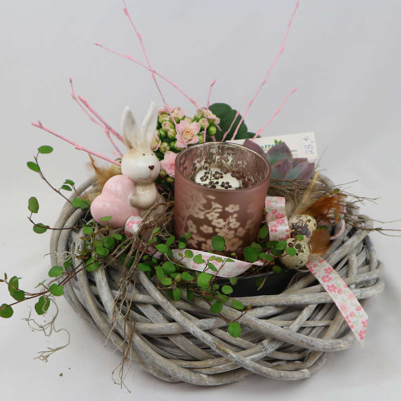Eine mit Muehlenbeckia, Kalanchoe und Sukkulenten bepflanzte Schale mit Hasenfigur und Kerzenglas.