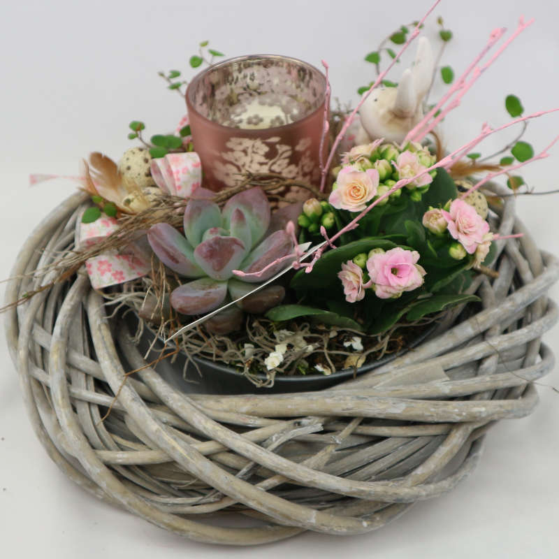 Eine mit Muehlenbeckia, Kalanchoe und Sukkulenten bepflanzte Schale mit Hasenfigur und Kerzenglas.