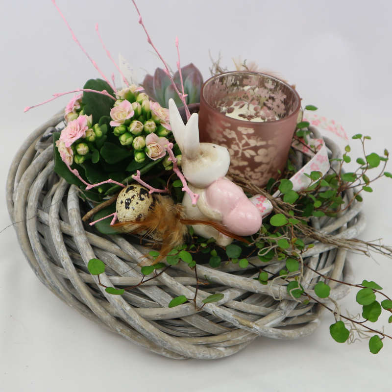 Eine mit Muehlenbeckia, Kalanchoe und Sukkulenten bepflanzte Schale mit Hasenfigur und Kerzenglas.